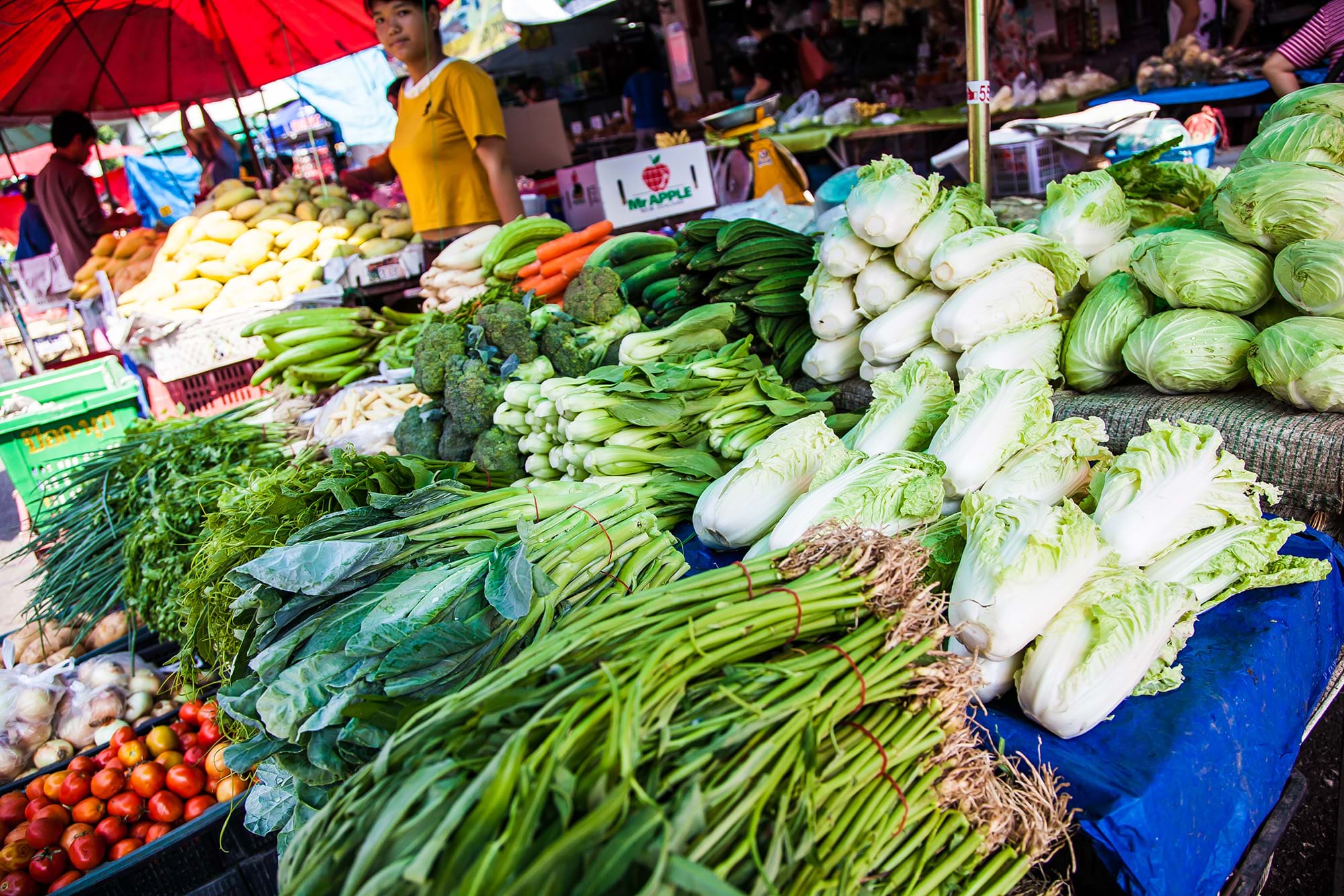 A market stall covered in green vegetables.